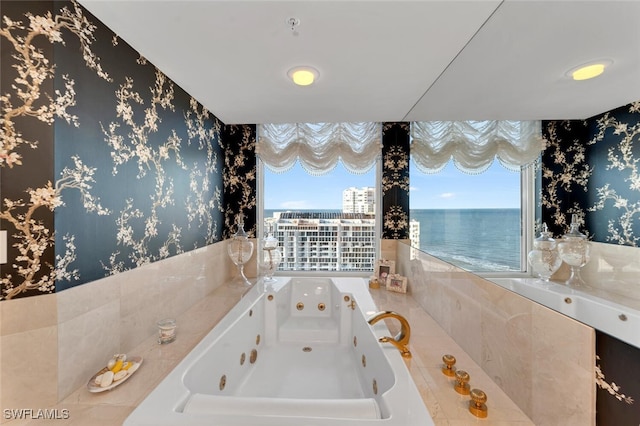 bathroom featuring plenty of natural light, a water view, and tiled tub