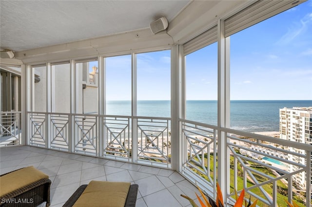 unfurnished sunroom with a water view and a view of the beach