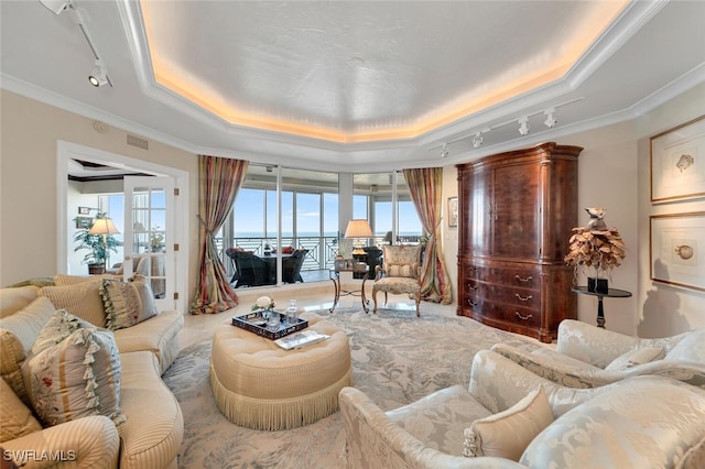 living room with a tray ceiling, a wealth of natural light, a water view, and rail lighting