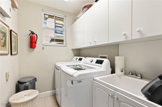 clothes washing area featuring cabinets, light tile patterned floors, sink, and washing machine and dryer