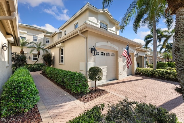 view of front of property featuring decorative driveway, a garage, and stucco siding