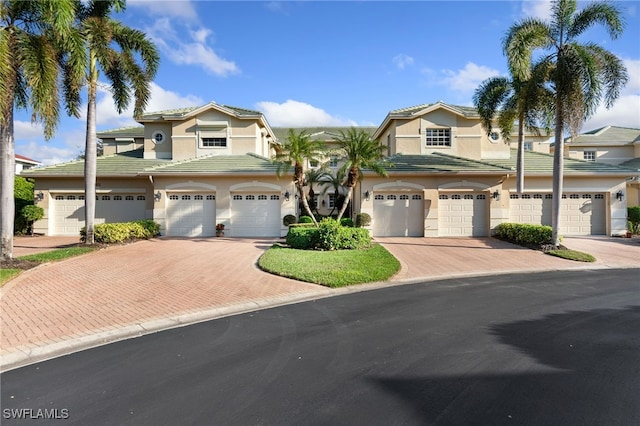 view of front of house featuring stucco siding, a tile roof, decorative driveway, and a garage