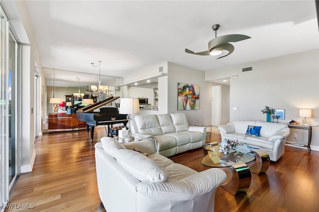 living room with wood-type flooring and ceiling fan with notable chandelier