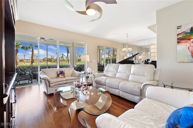 living room with ceiling fan with notable chandelier and dark wood-type flooring