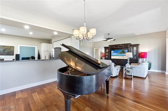 miscellaneous room featuring ceiling fan with notable chandelier and dark wood-type flooring