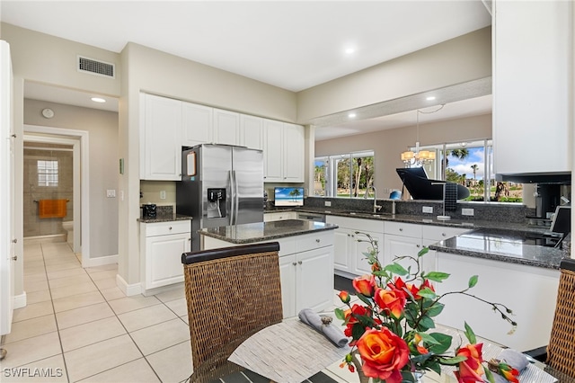 kitchen featuring visible vents, a sink, light tile patterned flooring, white cabinets, and stainless steel fridge with ice dispenser