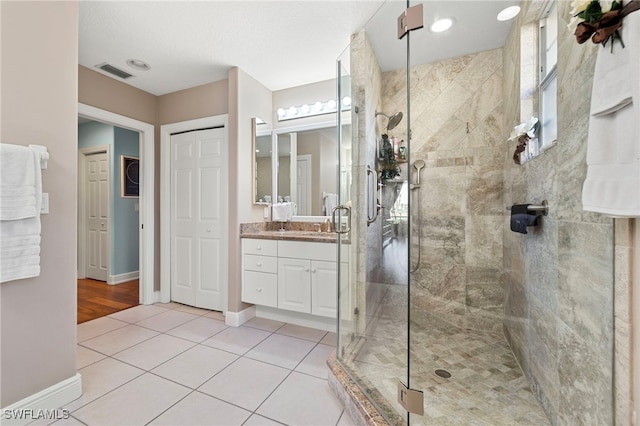 bathroom with tile patterned flooring, vanity, and a shower with door