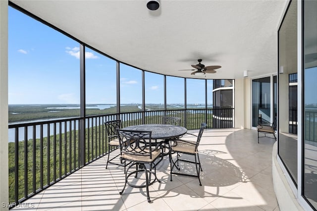 sunroom with a wealth of natural light, a water view, and ceiling fan