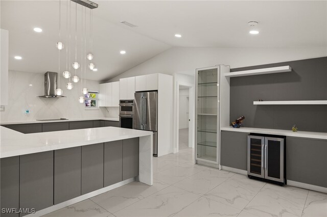 kitchen with pendant lighting, appliances with stainless steel finishes, white cabinets, beverage cooler, and wall chimney exhaust hood