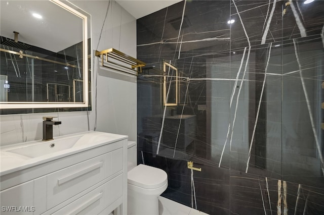 bathroom with a shower stall, vanity, tile walls, and toilet