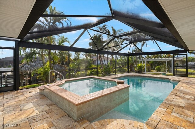 view of pool with a lanai, a patio, and an in ground hot tub