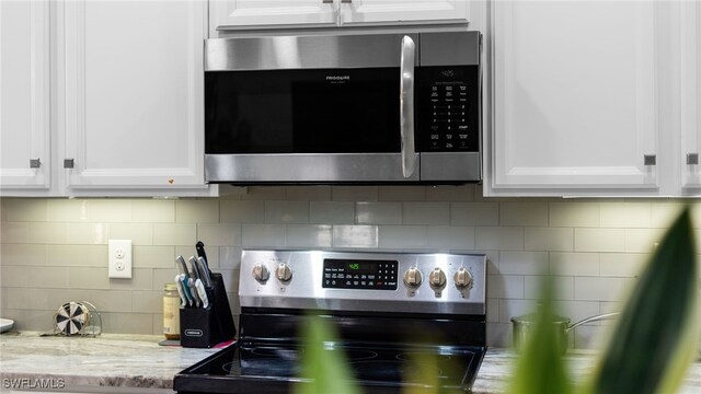 kitchen featuring white cabinets, appliances with stainless steel finishes, tasteful backsplash, and light stone counters