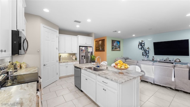 kitchen featuring stainless steel appliances, sink, light stone counters, a kitchen island with sink, and white cabinets