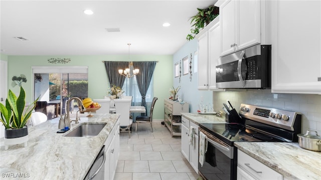 kitchen featuring white cabinetry, sink, appliances with stainless steel finishes, hanging light fixtures, and a notable chandelier