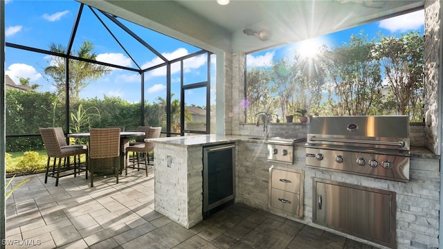 view of patio featuring a lanai, a grill, an outdoor wet bar, and exterior kitchen