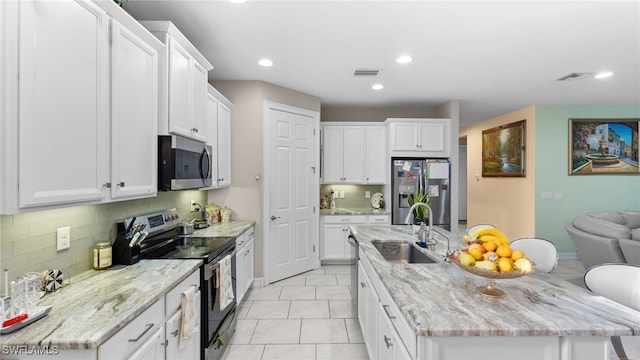 kitchen with stainless steel appliances, light tile patterned floors, decorative backsplash, sink, and white cabinets