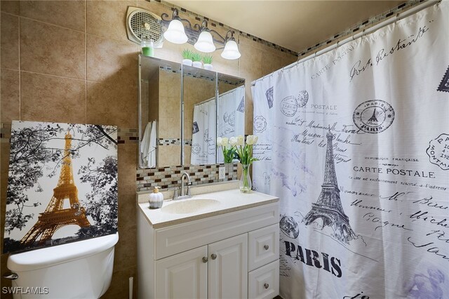 bathroom with decorative backsplash, toilet, tile walls, and vanity