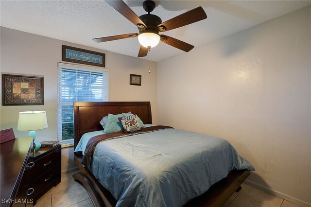 tiled bedroom with ceiling fan and a textured ceiling