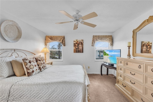 bedroom featuring multiple windows, ceiling fan, light carpet, and a textured ceiling