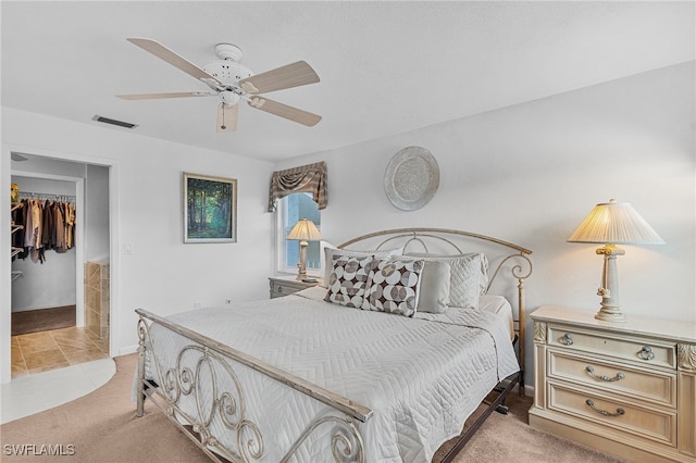 bedroom with ceiling fan, a walk in closet, light carpet, and a closet