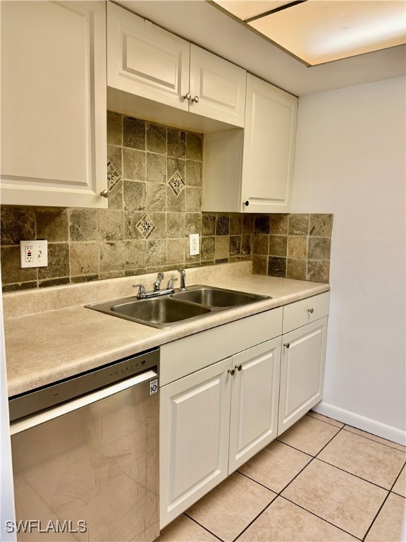 kitchen featuring white cabinetry, sink, stainless steel dishwasher, backsplash, and light tile patterned floors