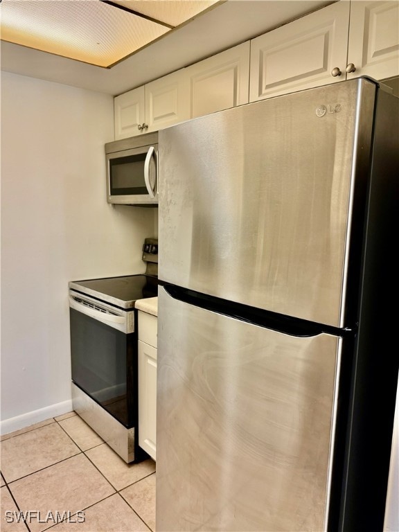 kitchen featuring white cabinets, appliances with stainless steel finishes, and light tile patterned floors