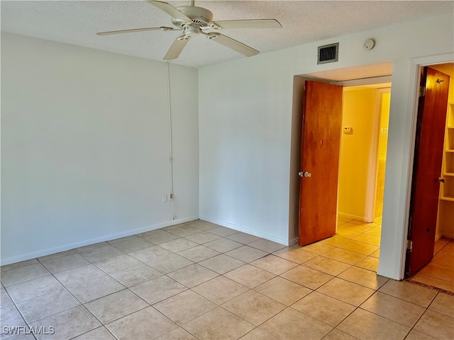 tiled empty room with ceiling fan and a textured ceiling