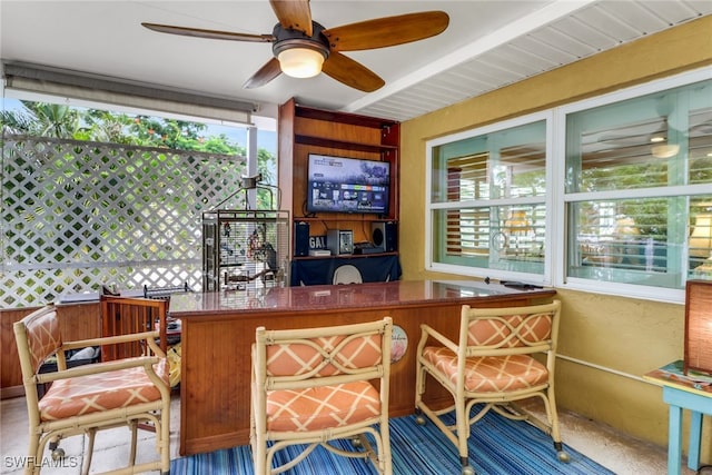 sunroom / solarium featuring ceiling fan and beam ceiling