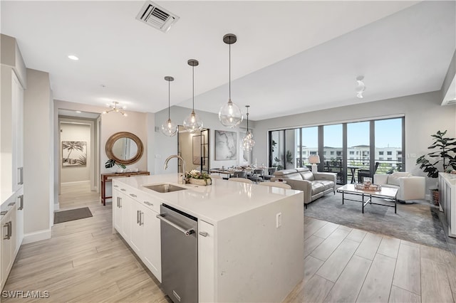 kitchen with pendant lighting, sink, an island with sink, stainless steel dishwasher, and white cabinetry