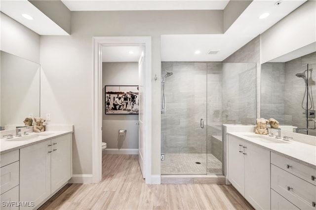 bathroom featuring hardwood / wood-style flooring, a shower with door, vanity, and toilet