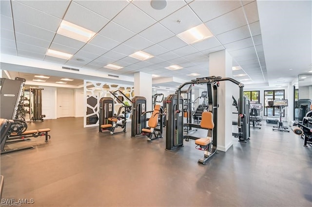 exercise room featuring a paneled ceiling and concrete floors