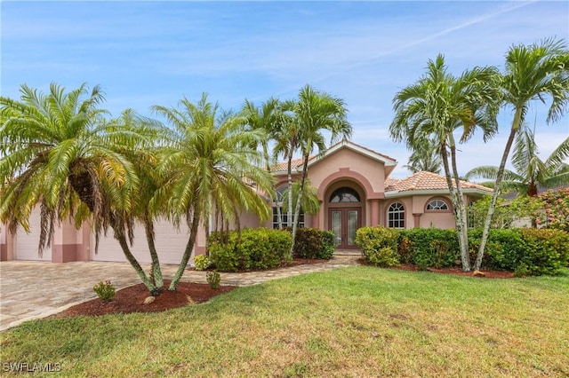 mediterranean / spanish house with a garage, a front yard, and french doors