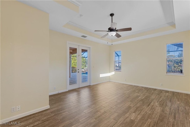 empty room featuring french doors, wood-type flooring, ceiling fan, and a tray ceiling