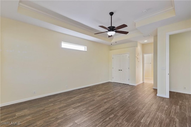 unfurnished bedroom with dark wood-type flooring, crown molding, a raised ceiling, a closet, and ceiling fan