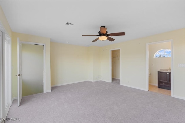 unfurnished bedroom featuring connected bathroom, light colored carpet, and ceiling fan