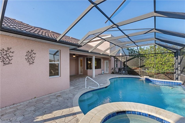 view of pool with a patio area, an in ground hot tub, and glass enclosure