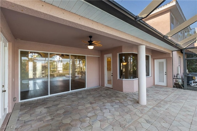 view of patio with ceiling fan and glass enclosure