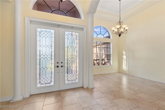 tiled foyer with french doors, a chandelier, and decorative columns