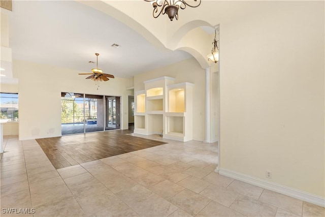 spare room featuring ceiling fan with notable chandelier and built in features