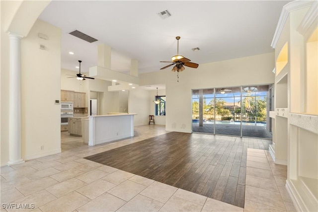 unfurnished living room with ceiling fan, a healthy amount of sunlight, and ornate columns