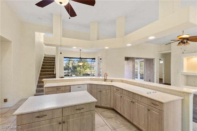 kitchen featuring white appliances, light tile patterned flooring, light brown cabinets, and a center island with sink