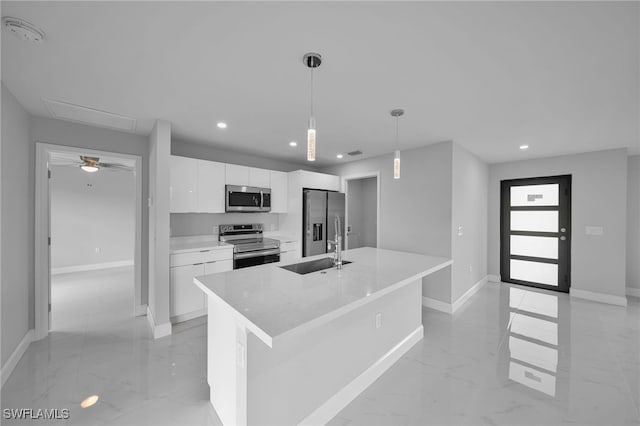 kitchen with sink, appliances with stainless steel finishes, a kitchen island with sink, white cabinets, and pendant lighting