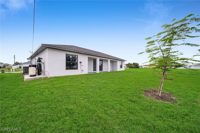 rear view of property featuring central AC unit and a yard