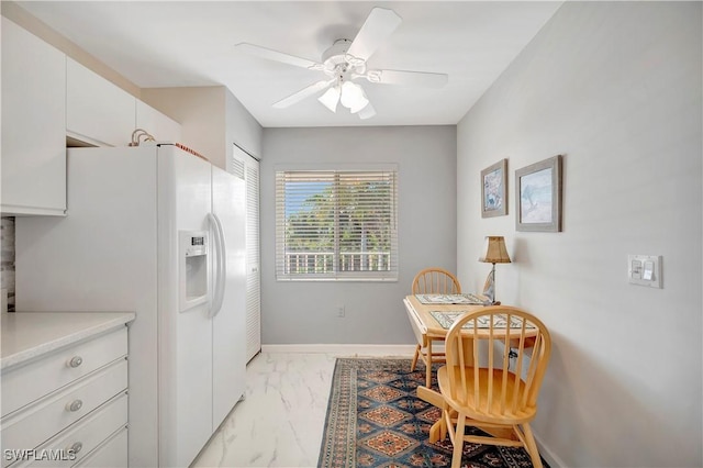 3032 Sandpiper Bay Cir Unit G305, Naples, FL 34112 - kitchen featuring white refrigerator with ice dispenser, white cabinetry, a ceiling fan, light marble finish flooring, and baseboards