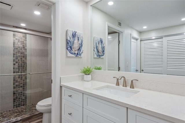 bathroom with vanity, toilet, and a shower with shower door