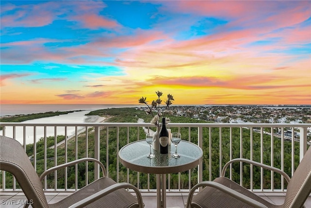 balcony at dusk featuring a water view