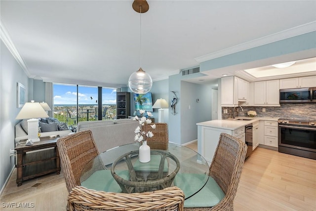 dining area featuring sink, crown molding, and light hardwood / wood-style flooring