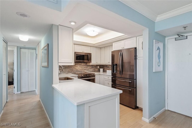 kitchen with white cabinets, appliances with stainless steel finishes, light wood-type flooring, and kitchen peninsula