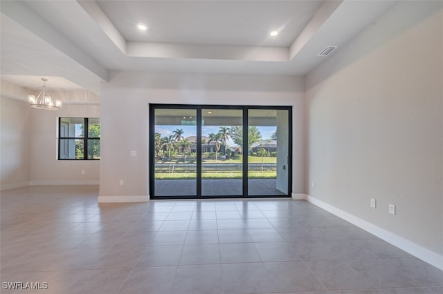 unfurnished room featuring a notable chandelier, light tile patterned floors, and a tray ceiling