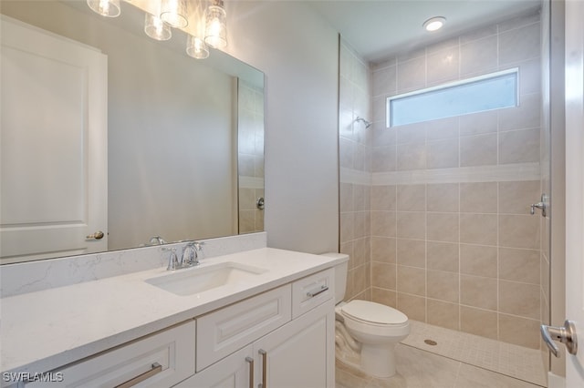 bathroom with toilet, tile patterned flooring, vanity, and tiled shower